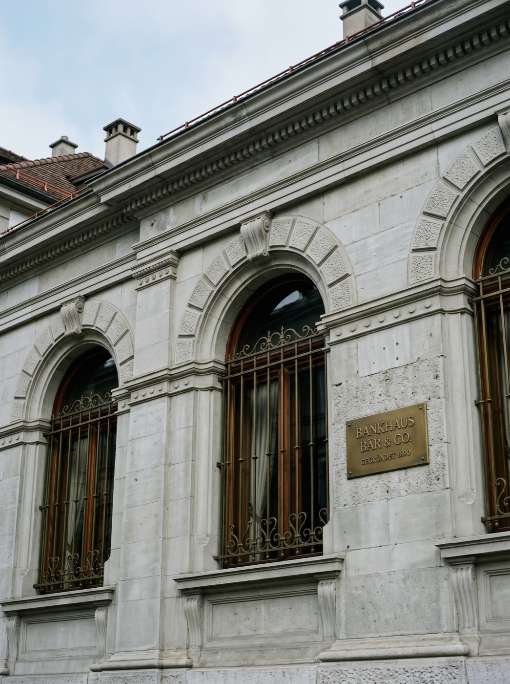 Zurich private bank facade – stone, brass nameplate, morning light
